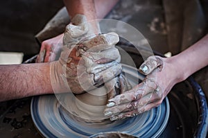 Woman and man hands. Potter at work. Creating dishes. Potter`s wheel. Dirty hands in the clay and the potter`s wheel