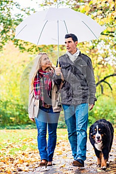 Woman and man having walk with dog in autumn rain