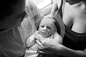 Woman and man holding on hands a newborn. Mom, dad and baby. Portrait of young family. Happy family life. Man was born