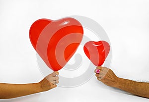 A woman and a man are holding heart-shaped balloons in their hands. Valentine`s day