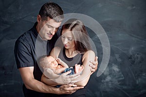 Woman and man holding a newborn. Mom, dad and baby. Close-up. Portrait of  smiling family with newborn on the hands. Happy family