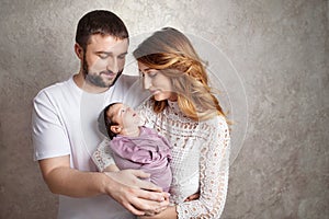 Woman and man holding a newborn. Mom, dad and baby.  Portrait of  smiling family with newborn on the hands. Happy family concept.