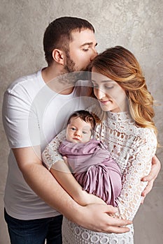 Woman and man holding a newborn. Mom, dad and baby. Portrait of  smiling family with newborn on the hands. Happy family concept