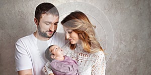 Woman and man holding a newborn. Mom, dad and baby.  Portrait of  smiling family with newborn on the hands. Happy family concept.