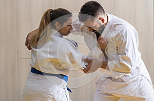 Woman and man judo fighters in sport hall