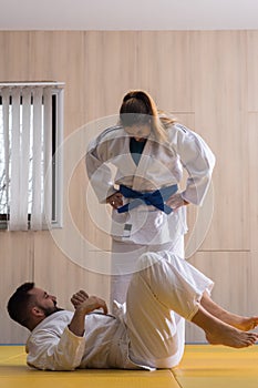 Woman and man judo fighters in sport hall