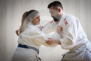 Woman and man judo fighters in sport hall