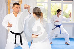 Woman and man in kimono sparring together in sport gym during karate training