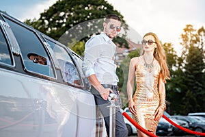 Woman and man leaning against a limo car