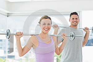 Woman and man lifting barbells at fitness studio