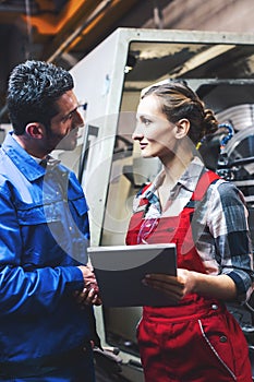 Woman and man manufacturing worker in discussion