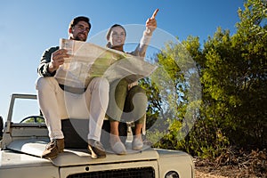 Woman with man pointing on off road vehicle with tire