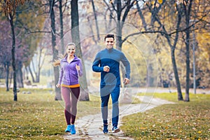 Woman and man running in autumn park for sport