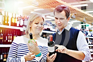 Woman and man selected bottle of wine in shop