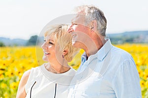 Woman and man, seniors, standing at sunflower field