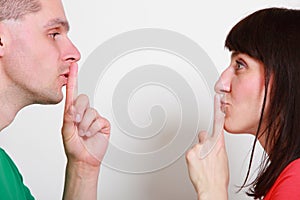 Woman and man showing hand silence sign