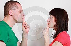 Woman and man showing hand silence sign
