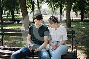 Woman and man sitting on bench and looking at camera display