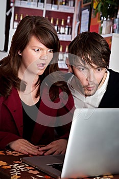 Woman and man staring with shock at laptop