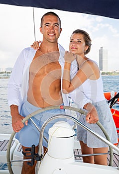 Woman and man steering yacht along shoreline of Spain