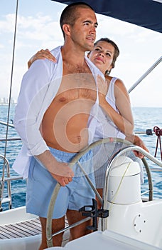 Woman and man steering yacht along shoreline of Spain