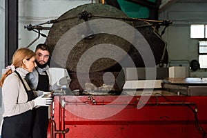 Woman and man supervising milling olives in crusher machine