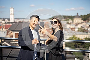 Woman and man take selfie on smartphone on balcony