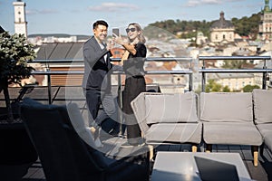 Woman and man take selfie on smartphone on balcony