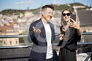 Woman and man take selfie on smartphone on balcony