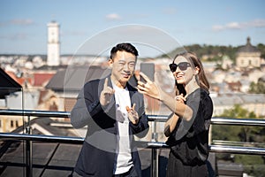 Woman and man take selfie on smartphone on balcony