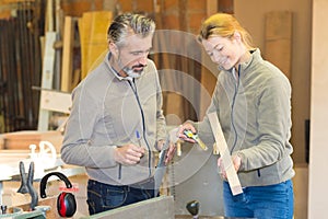 Woman and man teamwork at carpentry shop