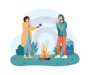 Woman and man travelers standing near campfire. Girl in blanket giving hot drink to boy for warming up