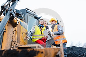 Woman and man worker in quarry on excavation machine