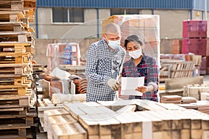 Woman manager in face mask discussing order list with man worker