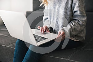 Woman manager sits on the sofa typing at her laptop , cozy office atmosphere concept