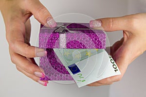 A woman with a manicure holding a gift box full of euro banknotes.