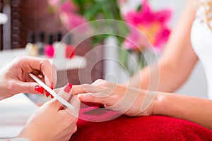 Woman at manicure in nail parlor with file