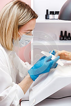 Woman on manicure treatment in beauty salon. Manicure, beauty procedures and personal care. Portrait