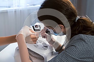 Woman manicurist cleaning pterygium near cuticle using apparatus for manicure. photo