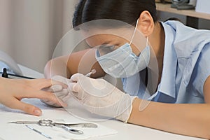 Woman manicurist master is removing cuticle and pterygium using pusher. photo