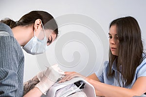 Woman manicurist is pushing cuticle on client`s fingers using wooden stick.