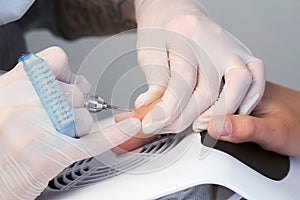 Woman manicurist removing cuticle and pterygium using apparatus, closeup view. photo