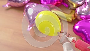 Woman is manual pumping putting air into shaped balloon for preparing holiday party decoration at home with inflator, close up, 4K