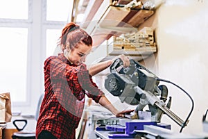 Woman manual worker operating tools in workshop