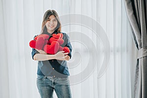 Woman with many heart shaped red pillow in her arms. Valentine day