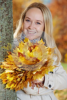 Woman with maple leaves at autumn