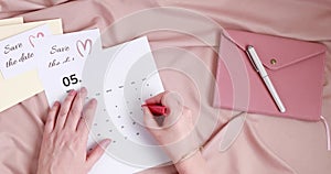 Woman marks date in calendar. Save the date card and envelope. Wedding planning, invitation concept