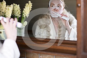 a woman in a mask brushing her teeth with an electric toothbrush