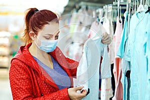 Woman in mask buying children clothes in department store during pandemic