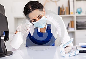 Woman in mask disinfecting office